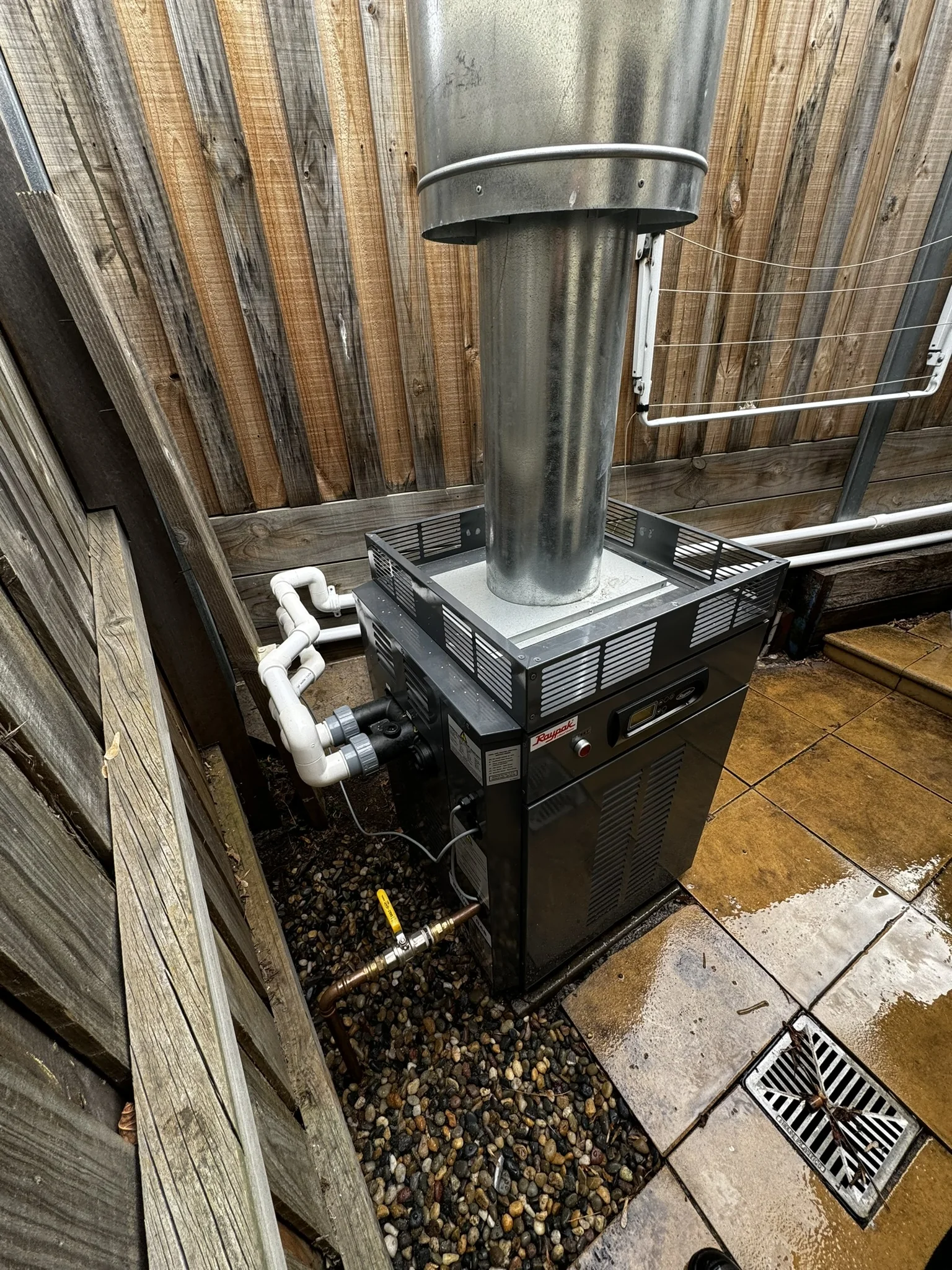 Pool filtration equipment installed beside a timber fence.